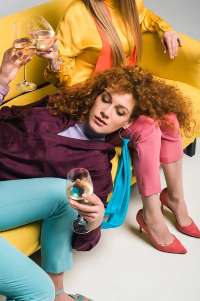 Vue aérienne de la rousse femme couchée sur le canapé et tenant verre de champagne près des filles sur blanc — Photo de stock