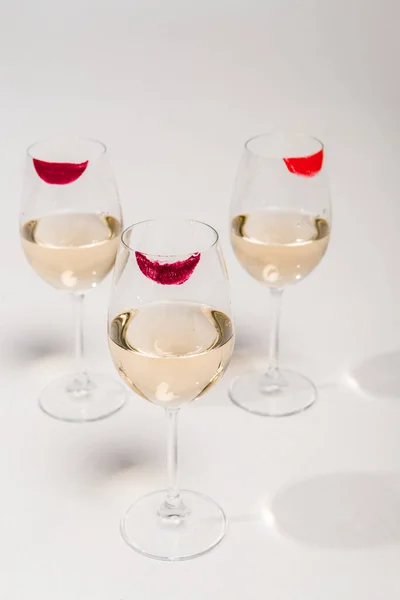 Lipstick prints on champagne glasses with alcohol on white — Stock Photo
