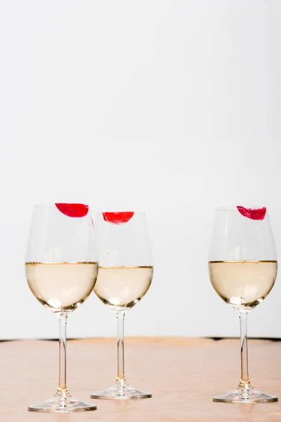 Красные отпечатки помады на бокалах для шампанского с алкоголем на белом — стоковое фото