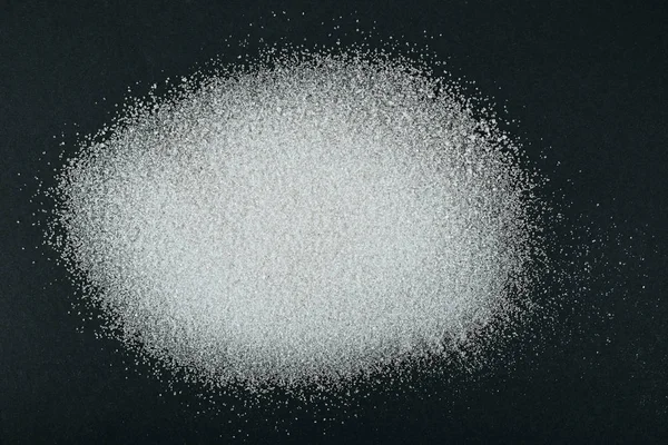 Top view of white granulated sugar crystals on black background — Stock Photo