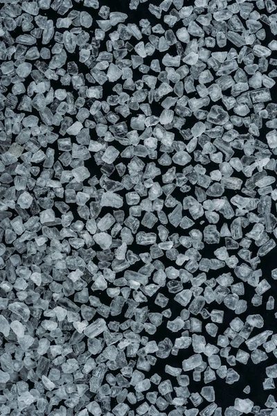 Vue de dessus des cristaux de sucre sucré blanc sur la surface noire — Photo de stock