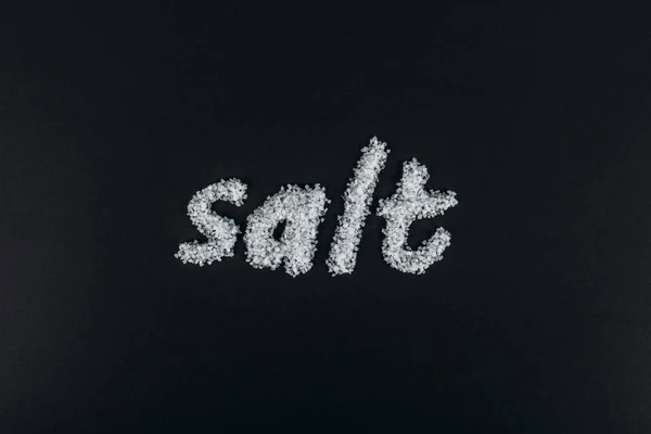 Vista superior de la palabra sal hecha de cristales de sal sobre fondo negro - foto de stock