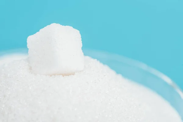 Weißer Zuckerwürfel auf Zuckerkristallen isoliert auf blau — Stockfoto