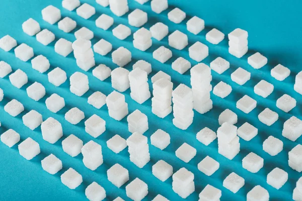 White sugar cubes arranged in rows and stacks on blue surface — Stock Photo