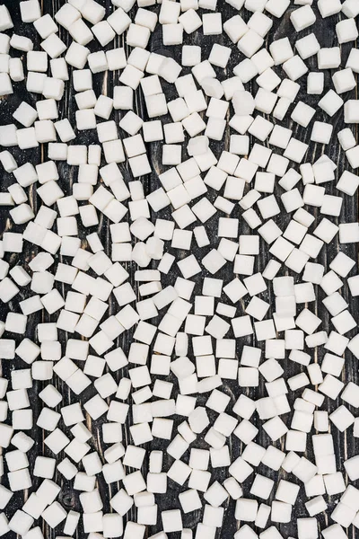 Top view of white sugar cubes on black wooden surface — Stock Photo