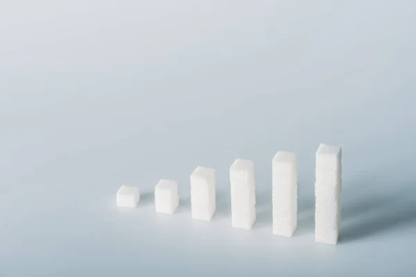 Stacks of white sugar cubes on grey background with copy space — Stock Photo