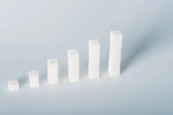 Білі кубики цукру розташовані в стосах на сірому фоні з копіювальним простором — стокове фото