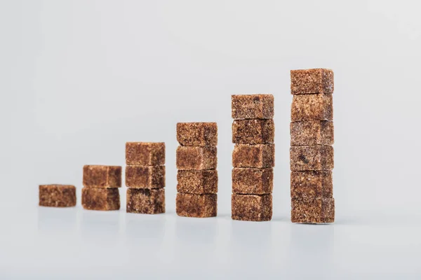 Stack of brown sugar cubes arranged on grey background — Stock Photo