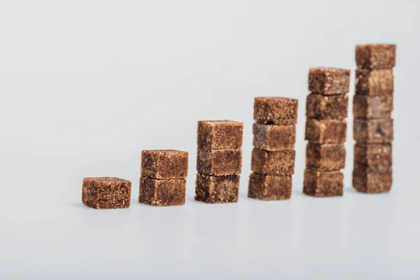 Brown sugar cubes arranged in stacks on grey background — Stock Photo