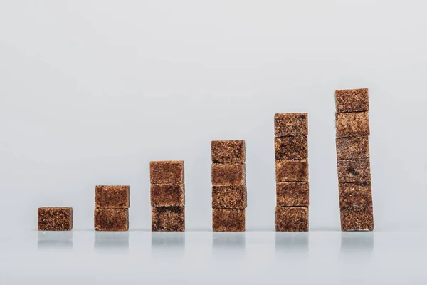 Стопки коричневих кубиків цукру на сірому фоні з копіювальним простором — стокове фото