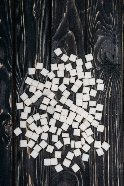 Вид сверху на кубики белого сахара на черном деревянном фоне — стоковое фото