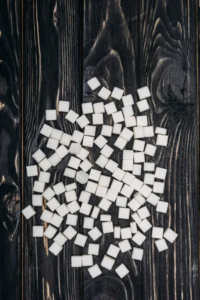 Top view of white sugar cubes on black wooden background — Stock Photo