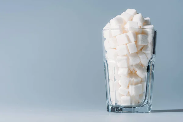 Склянка з вишуканими білими кубиками цукру на сірому фоні з місцем для тексту — стокове фото