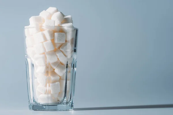 Cubetti di zucchero bianco in vetro su sfondo grigio con spazio copia — Foto stock