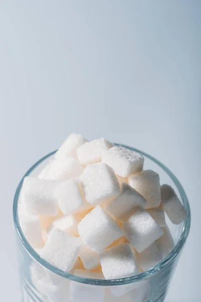 White sweet sugar cubes in glass on grey background — Stock Photo