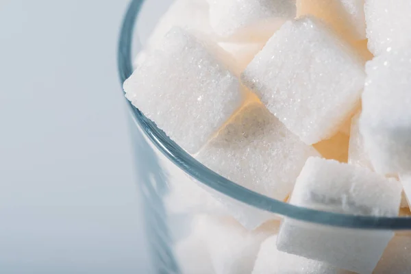 Primo piano vista di cubetti di zucchero bianco in vetro su sfondo grigio — Foto stock