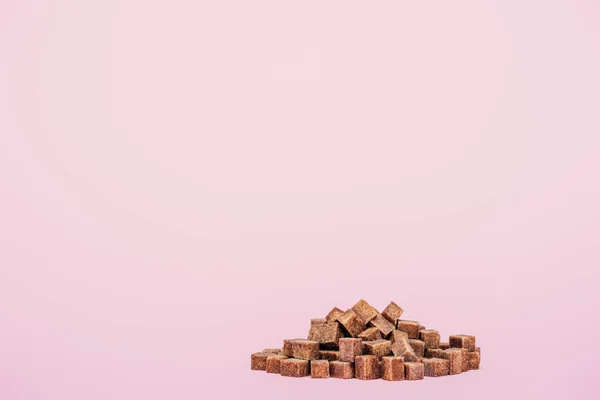 Pile of brown sugar cubes on pink background with copy space — Stock Photo