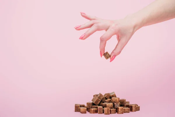 Vue recadrée femme avec poignée de cubes de sucre blanc sur isolé sur rose — Photo de stock