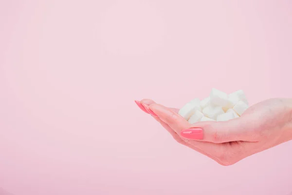 Vista recortada de la mujer con un puñado de cubos de azúcar blanco aislado en rosa - foto de stock