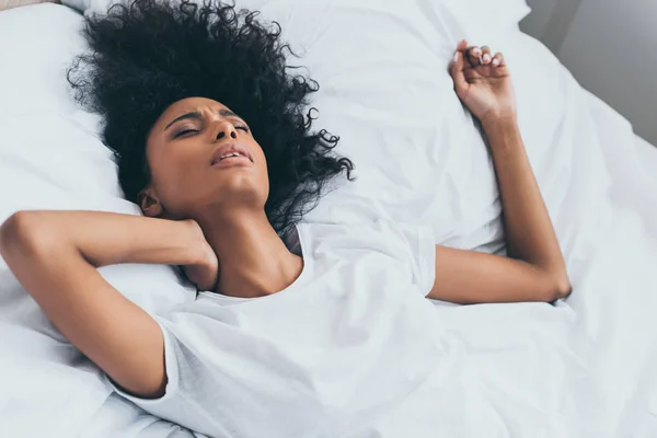 Bela mulher afro-americana sofrendo de dor no pescoço enquanto deitada na cama — Fotografia de Stock