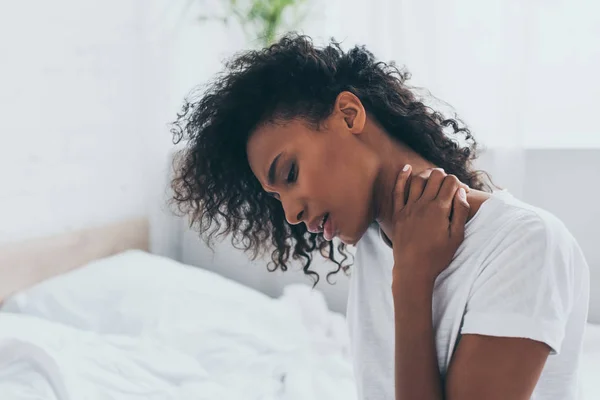 Unglückliche Afroamerikanerin leidet unter Nackenschmerzen im Schlafzimmer — Stockfoto