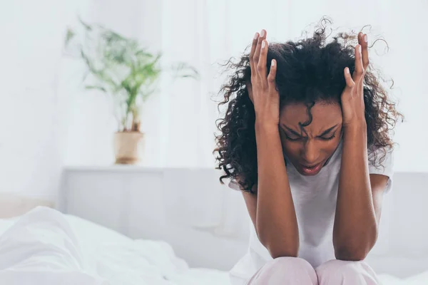 Exhausted african american woman suffering from headache in bedroom — Stock Photo