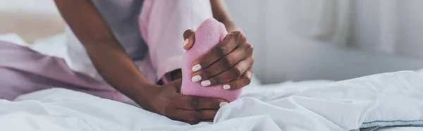 Panoramic shot of african american woman suffering from foot pain in bedroom — Stock Photo