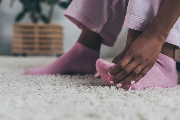Selective focus of african american woman suffering from foot pain in bedroom — Stock Photo