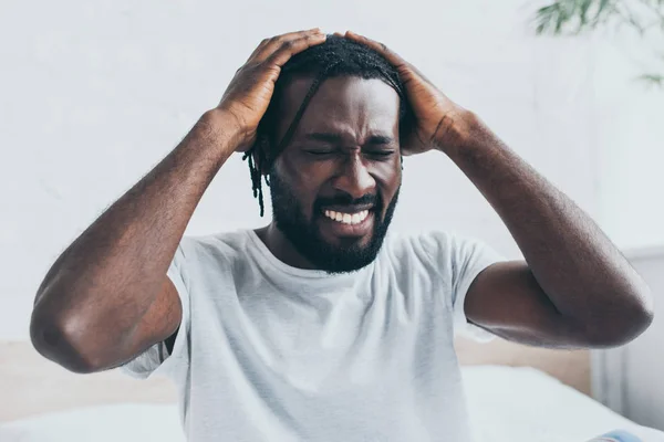 Malheureux homme afro-américain souffrant de maux de tête dans la chambre — Photo de stock