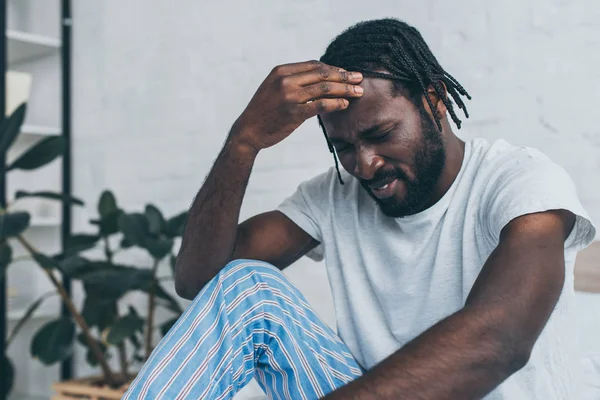 Tired african american man suffering from headache in bedroom — Stock Photo