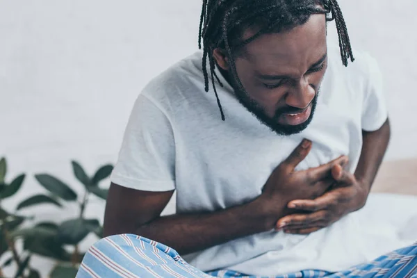 Junger afrikanisch-amerikanischer Mann leidet unter Herzschmerzen im Schlafzimmer — Stockfoto