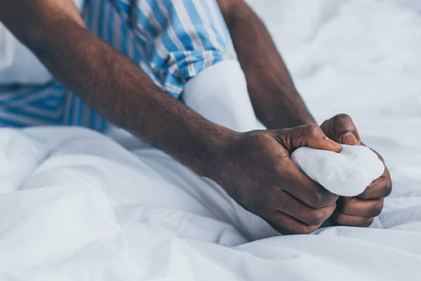 Messa a fuoco selettiva dell'uomo afro-americano che soffre di dolore ai piedi in camera da letto — Foto stock