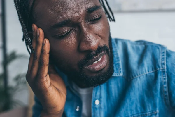 Unhappy african american man holding hand near head while suffering from headache — Stock Photo