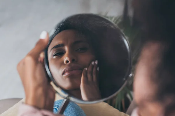 Mujer afroamericana molesta mirando el espejo mientras sufre de dolor en la mandíbula - foto de stock