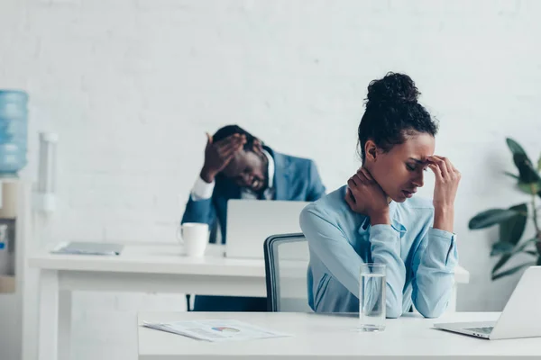 Gestores afro-americanos sentados em locais de trabalho e com dores de cabeça — Fotografia de Stock