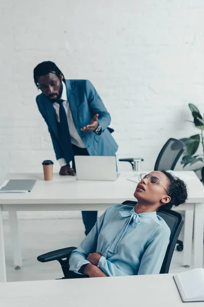 Femme d'affaires épuisée souffrant de douleurs abdominales près d'un collègue afro-américain — Photo de stock