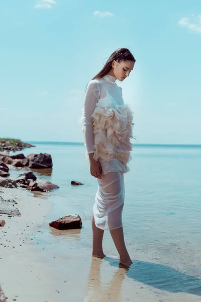 Jeune femme en costume de cygne blanc marchant sur la plage — Photo de stock