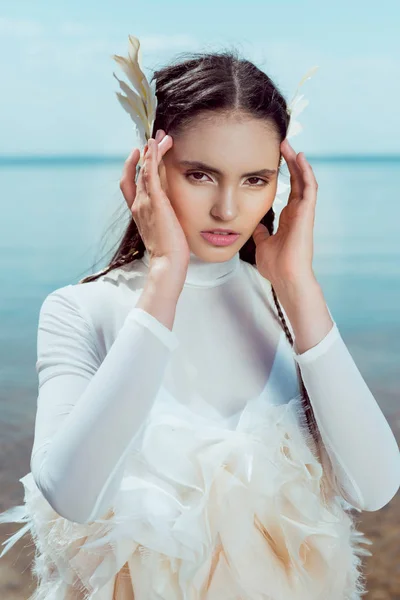 Portrait of adult woman in white swan costume looking at camera, holding hands near face — Stock Photo