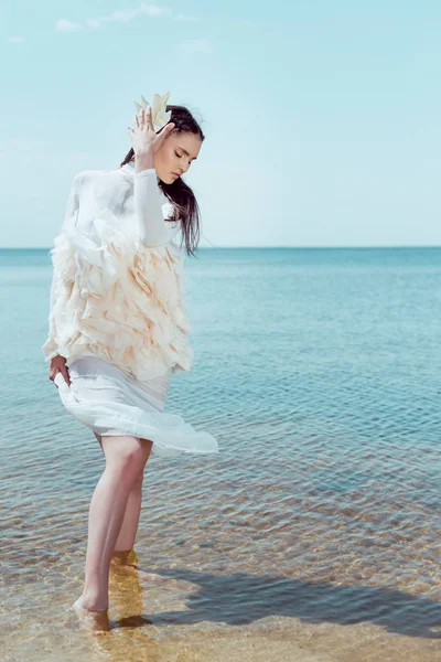 Hermosa mujer en traje de cisne blanco de pie sobre fondo de arena - foto de stock