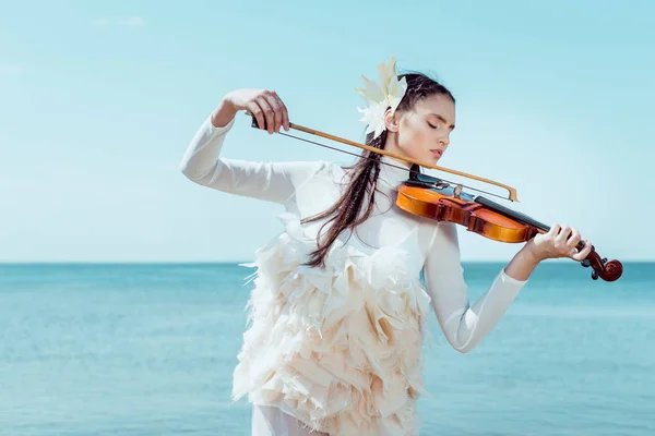Tender woman in white swan costume playing on violin — Stock Photo