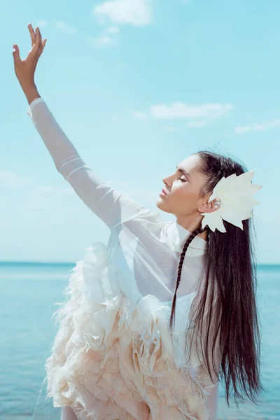 Donna sognante in costume da cigno bianco occhi di chiusura, in piedi su sfondo cielo blu — Foto stock