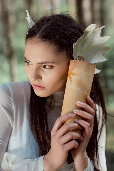 Porträt einer jungen Frau im weißen Schwanenkostüm, die eine Schriftrolle in der Hand hält und wegschaut — Stockfoto