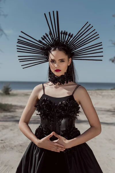 Mujer joven en traje de bruja con corona en la cabeza mirando a la cámara - foto de stock