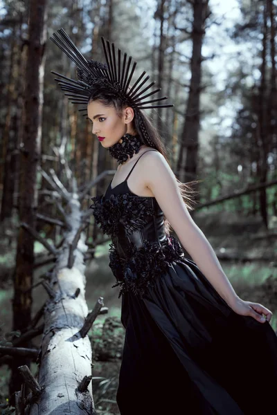 Femme brune en costume de sorcière debout sur fond de forêt — Photo de stock