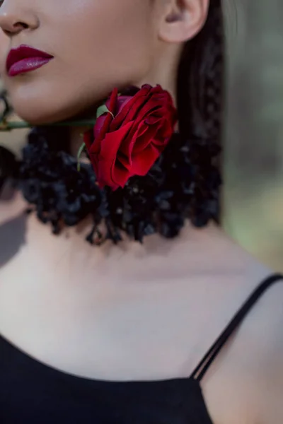 Vista cortada de mulher elegante em traje de bruxa segurando rosa vermelha perto do pescoço — Fotografia de Stock