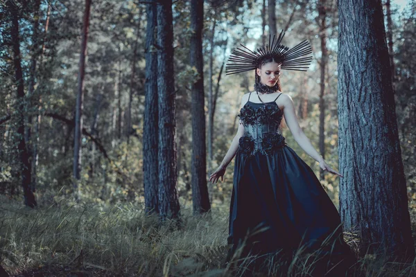 Schöne Frau im Hexenkostüm geht durch den Wald und schaut weg — Stockfoto