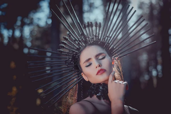 Retrato de mulher bonita em traje de bruxa com coroa na cabeça fechando os olhos, segurando as mãos perto do rosto — Fotografia de Stock