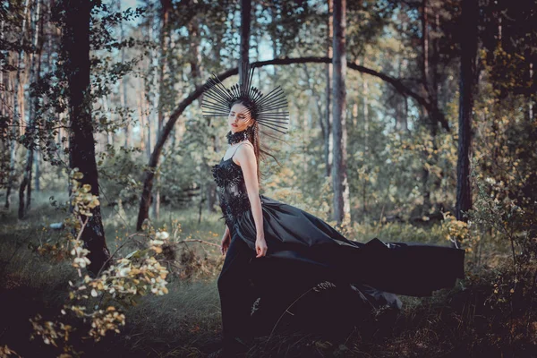 Bela mulher em bruxa traje de pé no fundo da floresta — Fotografia de Stock