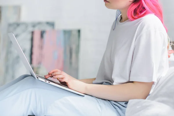 Vue partielle de la fille avec les cheveux roses en utilisant un ordinateur portable dans la chambre — Photo de stock