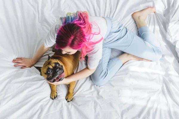 Top view of girl with colorful hair sitting in bed with dog — Stock Photo